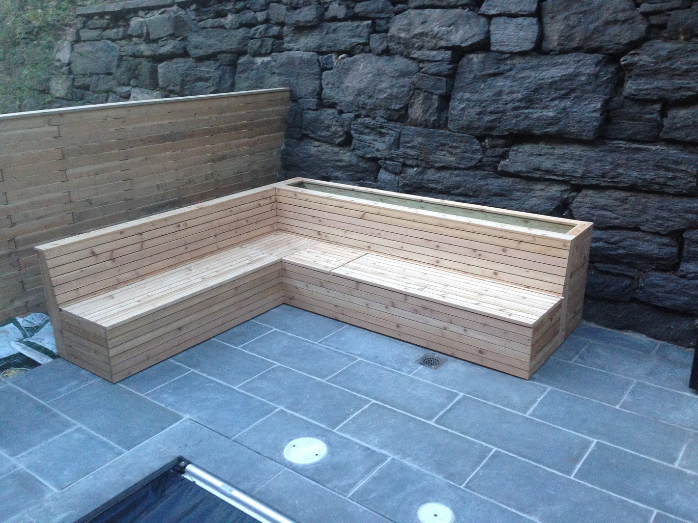 Custom outdoor knotty cedar bench with planter box and bluestone deck created by TCSC