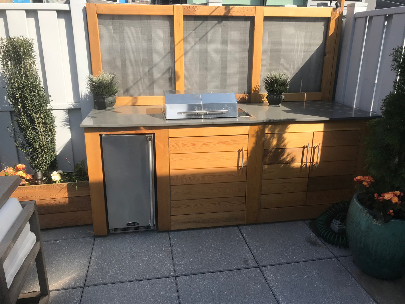 Custom backyard Kitchen with planter box and a gray countertop created by TCSC