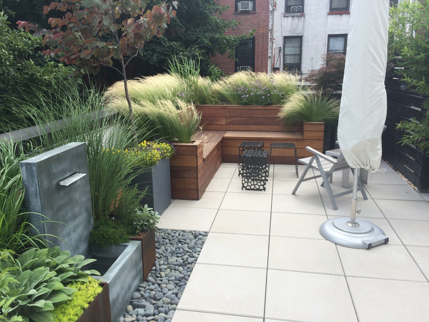 Custom ipe bench with built-in planters and stone waterfall with beach stones created by TCSC
