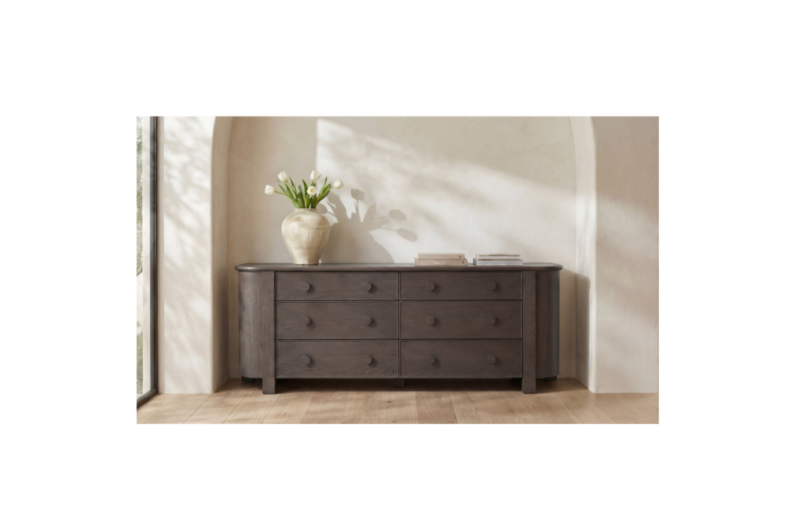 Dark wood dresser with a vase of flowers in a softly lit room