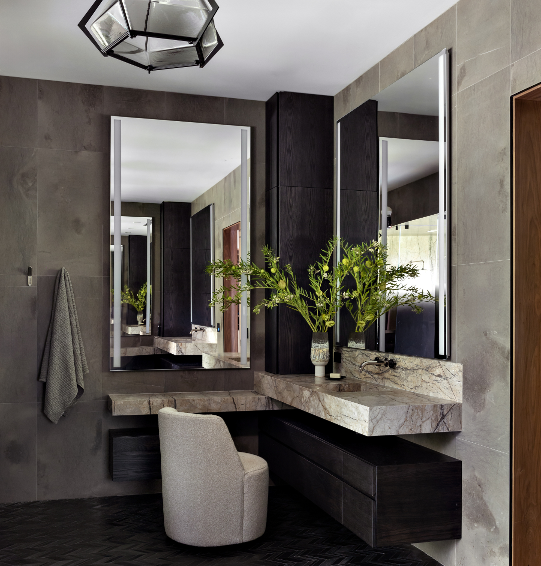 Modern bathroom with marble vanity, large mirrors, and decorative elements.