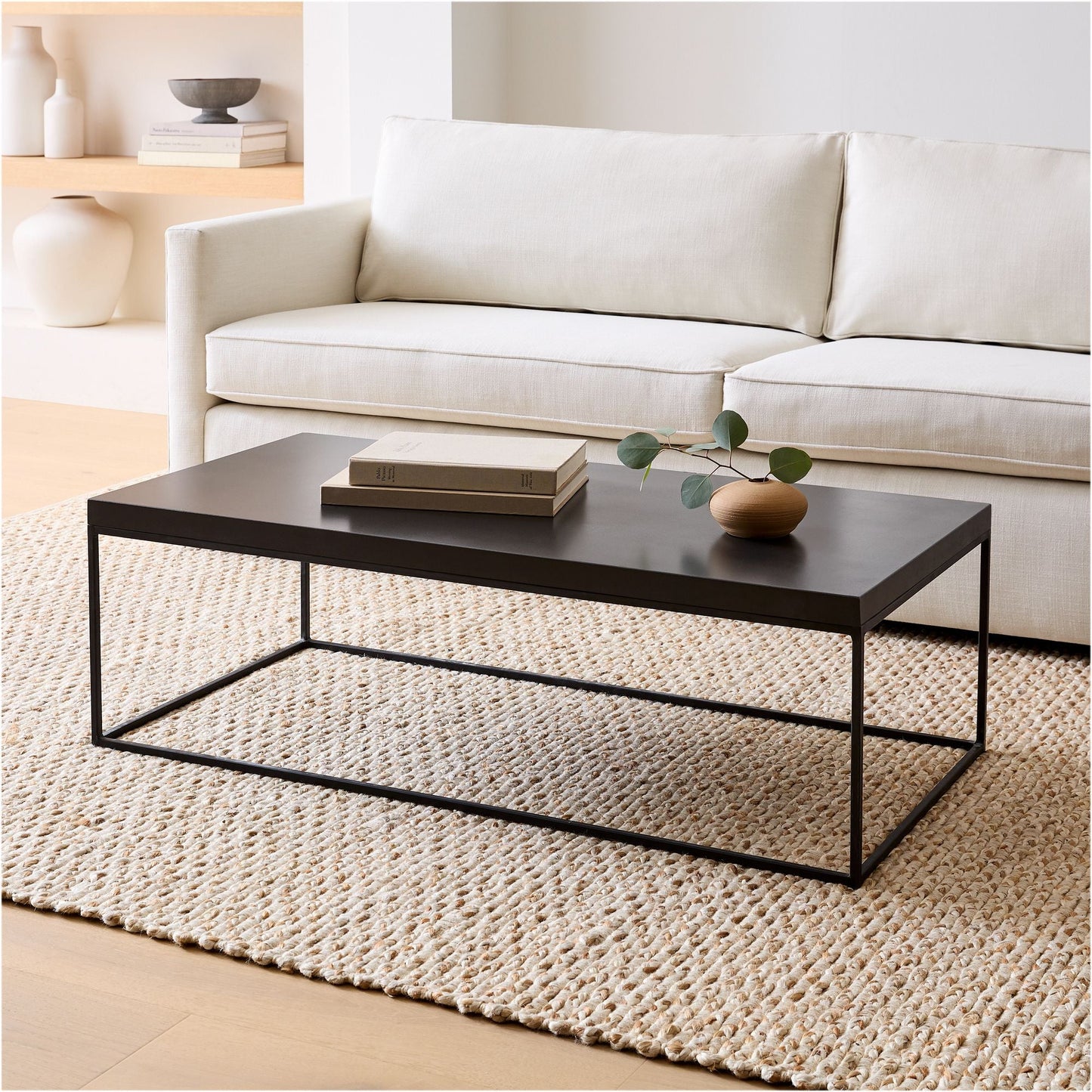 Black coffee table in a living room with a white sofa and decorative items.