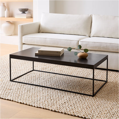 Black coffee table in a living room with a white sofa and decorative items.