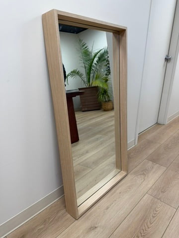 Full-length mirror with wooden frame on a wooden floor