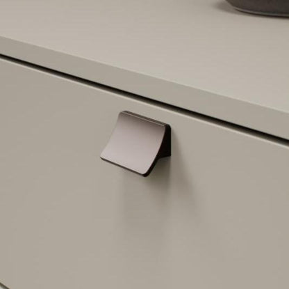 Metallic cabinet handle on a light gray cabinet door