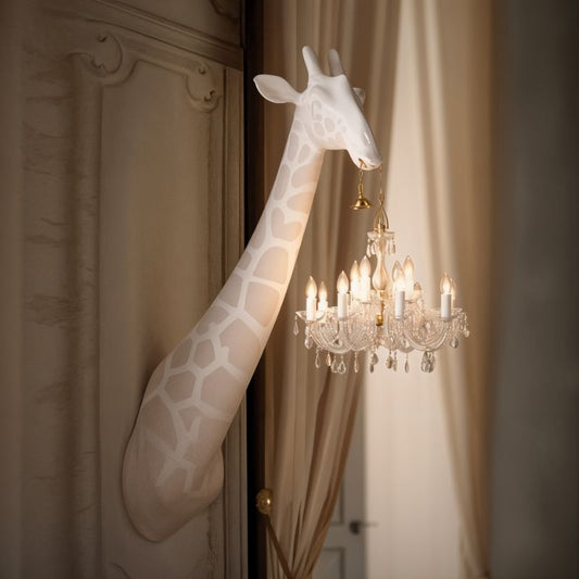 Decorative giraffe sculpture next to a chandelier in an elegant room.